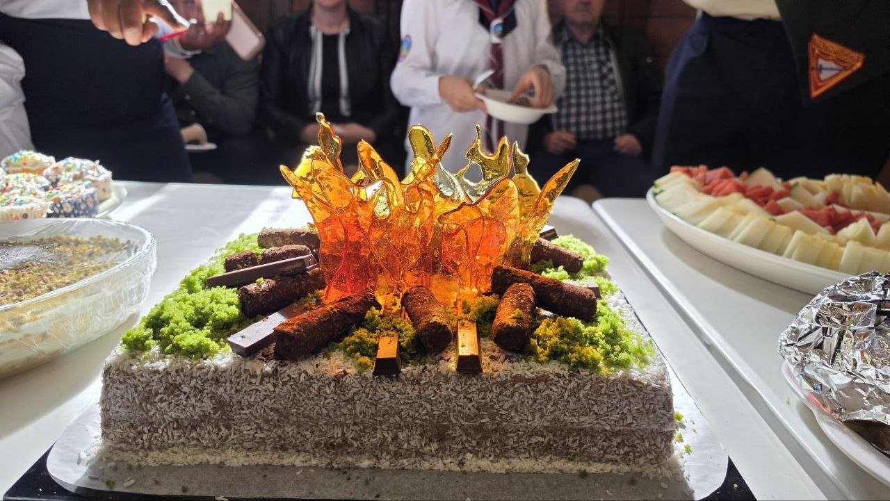 Celebration cake decorated as a campfire with orange sugar flames and chocolate logs